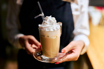 bartender holding a mug of latte coffee in the evening in a cafe