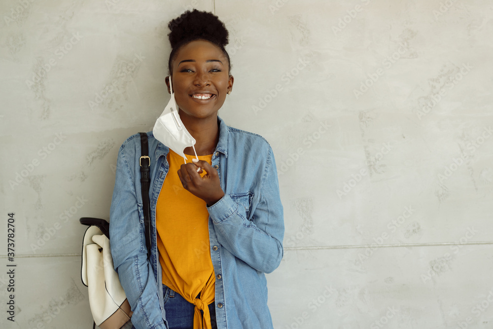 Poster Happy African American university student taking her protective mask off.