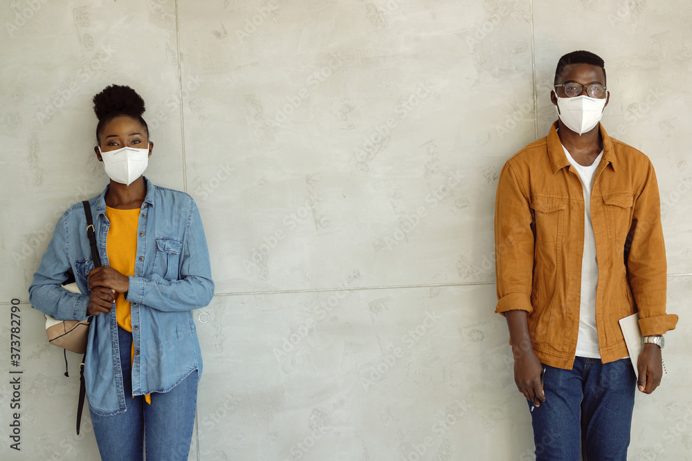 Canvas Prints Black students with face masks standing against the wall at safe distance.