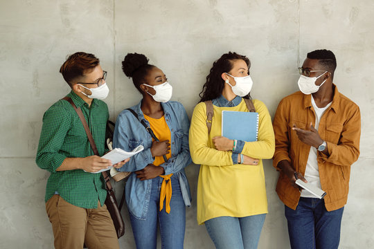 Multi-ethnic Group Of College Students With Face Masks Communicating Against The Wall.