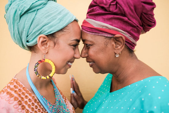 Happy african mother and daughter with forehead together and smiling - African people wearing traditional dress and turban