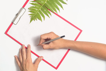 Female hands are writing on a white sheet of paper