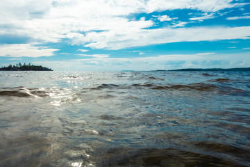 Deep cold blue water of Ladoga lake with sun light reflections under blue cloudy sky