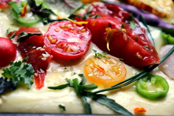 Tomatoes multicolored slices on a dough for a pie close-up before baking, selective focus.