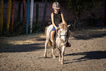 Young boy riding a pony at equestrian school