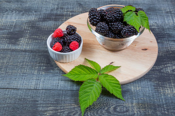 Fototapeta na wymiar ripe blackberry with leaves on on dark blue wooden background, rustic,