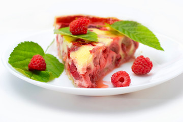raspberry piroke on a white table, garnished with raspberries and raspberry leaves.
