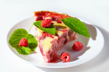 raspberry piroke on a white table, garnished with raspberries and raspberry leaves.
