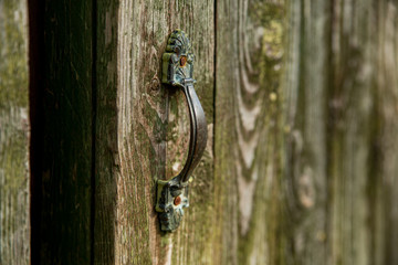Old iron handle on a wooden entrance door. Retro, vintage.