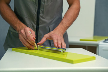 furniture assembly service. employee installs a handle on a furniture door. worker marks with a pencil the place where the furniture door handle will be attached