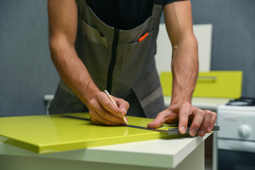 furniture assembly service. employee installs a handle on a furniture door. worker marks with a pencil the place where the furniture door handle will be attached
