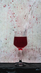 red wine splashing in a wine glass, with a white wooden texture in background.