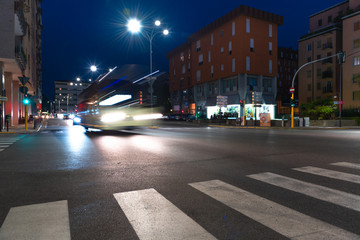 Fototapeta premium Timelapse view of traffic at an urban night intersection. Urban movement in the Italian city in the evening.