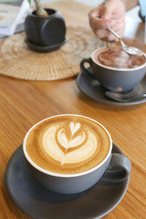 Hot coffee cup that are placed on the wooden table in the coffee shop.