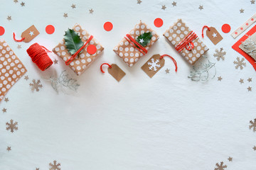 DIY Christmas gifts and handmade decorations. Natural plastic free eco-friendly Xmas celebration. Gift boxes in craft wrapping paper, geometric arrangement with fir twigs, toys on white textile.