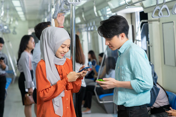 Muslim woman playing mobile phone with colleagues on her way to work