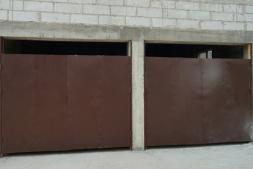 white brick garage facade with two brown iron gates on the street