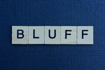 gray word bluff from small wooden letters on a black table