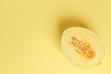 Half of yellow ripe sweet honeydew melon over yellow background. Vegetarian, raw food diet and healthy eating concept. Sweet fruits and berries. Copy space.