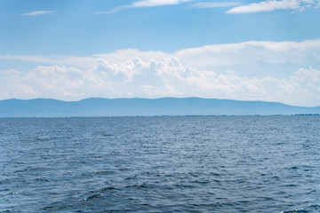 Russia, Irkutsk region, Baikal lake, July 2020: scenic landscape of smooth lake water with wooly...