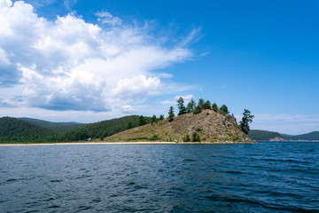 Obraz premium Russia, Irkutsk region, Baikal lake, July 2020: yellow sand cliff with rare trees in the lake