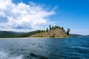 Naklejka premium Russia, Irkutsk region, Baikal lake, July 2020: yellow sand cliff with rare trees in the lake