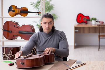 Young male repairman repairing cello