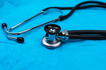 Black Stethoscope and phonendoscope on the blue nonwoven fabric. Selective focus. Medical concept. 