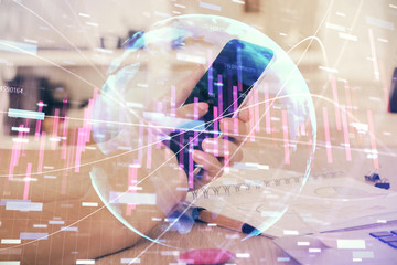Double exposure of man's hands holding and using a digital device and forex graph drawing. Financial market concept.