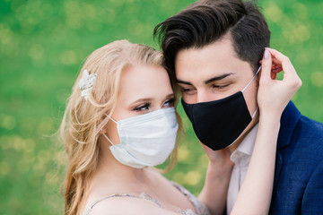 Young loving couple walking in medical masks in the park during quarantine on their wedding day. Coronavirus, disease, protection, sick, illness flu europe celebration canceled.