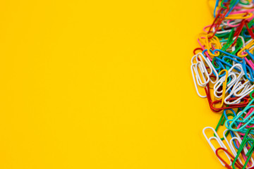Colorful paper clip on yellow background. Close up top view