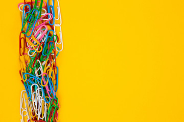 Colorful paper clip on yellow background. Close up top view