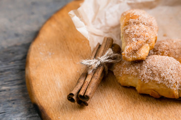 Fresh croissants with cinnamon on wrinkled paper on wooden background table