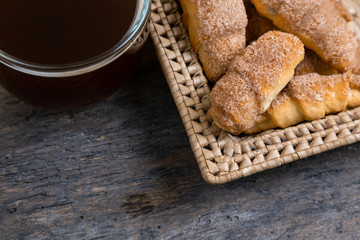 Croissants lie in a wicker basket with tea cup. A view from above of the pastry, which lies on a wooden background