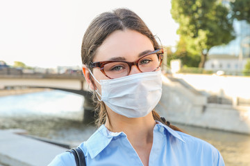 a girl with glasses and a mask on the river embankment