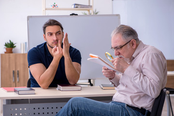 Old teacher and young male student in the classroom