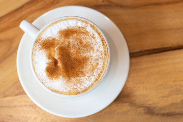 Coffee with cinnamon close-up on wooden background, top view