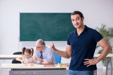 Young parent, old male teacher and little girl in the classroom