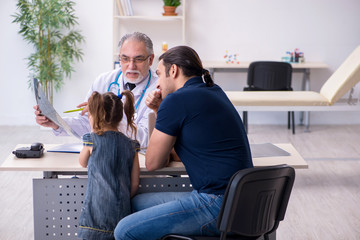 Young father and his daughter visiting old male doctor