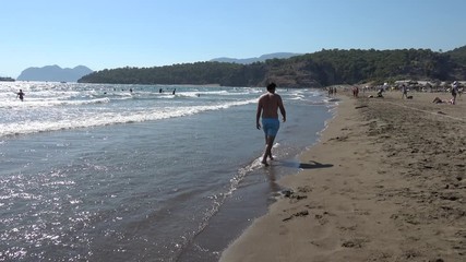 Iztuzu beach, Dalyan, Turkey - 17th of August 2020: 4K Man passes and walks away along sandy beach
