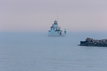 The lighthouse in the evening haze on the lake Michigan