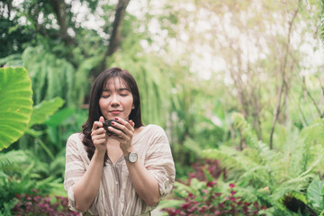 Young Asian woman relaxing at garden with a cup of coffee in a morning. A woman inhaled coffee