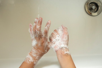 石鹸を泡立てて、手洗いする子供の手、洗面所