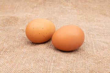 Brown eggs are laying on burlap or linen or jute fabric
