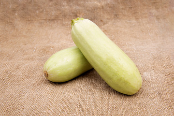 Fresh vegetable marrow or zucchini isolated on linen or jute sacking or fabric