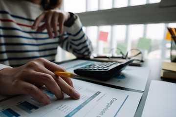 Business woman working in finance and accounting Analyze financial budget with calculator in the...