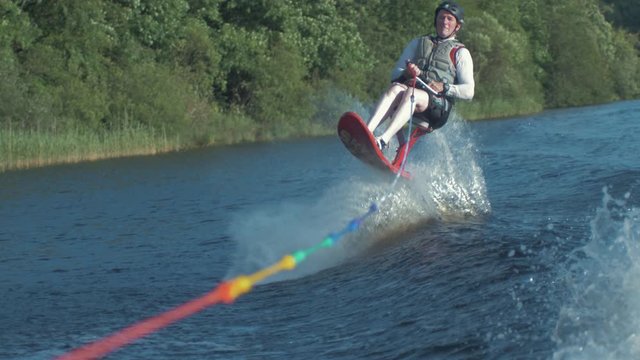 Man jumps boat wake on skyski air chair. Slow motion 4k