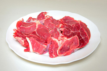 Raw beef meat steak on white plate on light background close up. Carnivore, keto