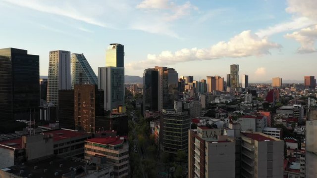 Vista a&eacute;rea durante el atardecer en la Ciudad de M&eacute;xico con el drone volando sobre Av. Insurgentes con vista al skyline de Paseo de la Reforma