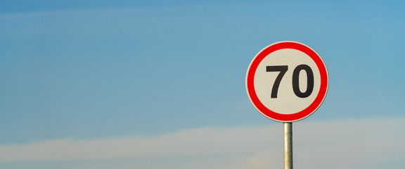 70 speed limit road sign over blue sky background